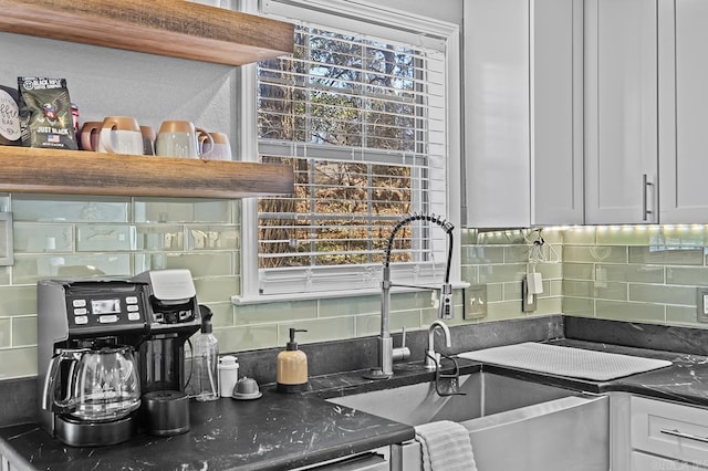 kitchen with tasteful backsplash, dark countertops, a sink, and white cabinets