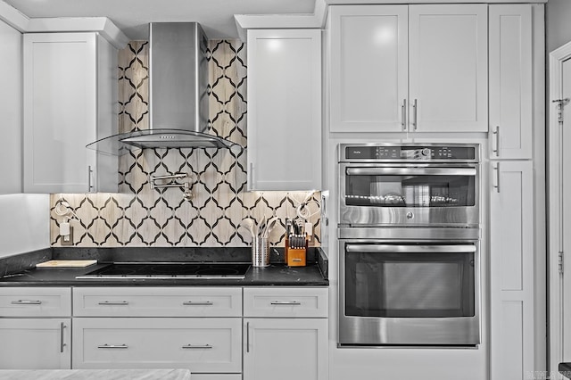 kitchen featuring dark countertops, wall chimney exhaust hood, black electric stovetop, and double oven