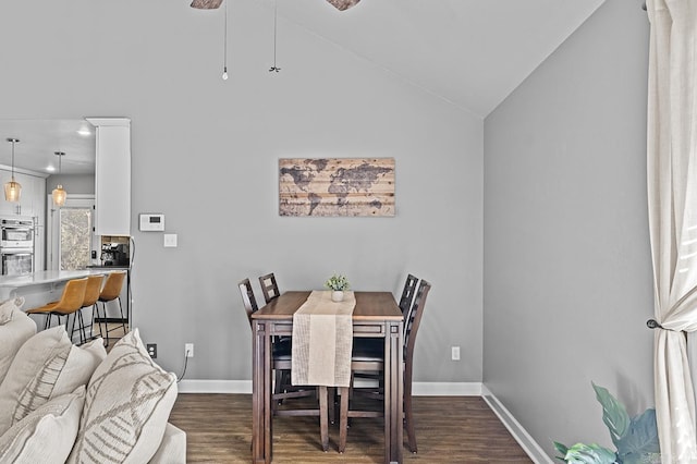 dining area featuring vaulted ceiling, dark wood finished floors, and baseboards