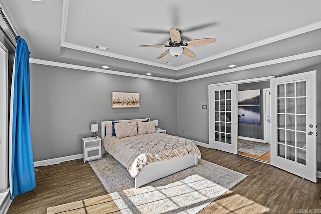 bedroom featuring visible vents, a tray ceiling, wood finished floors, and french doors