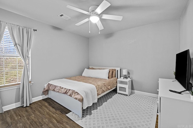 bedroom with a ceiling fan, wood finished floors, visible vents, and baseboards