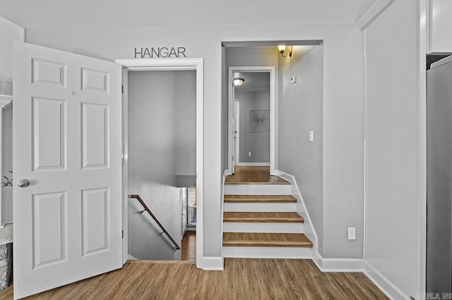 staircase featuring wood finished floors and baseboards