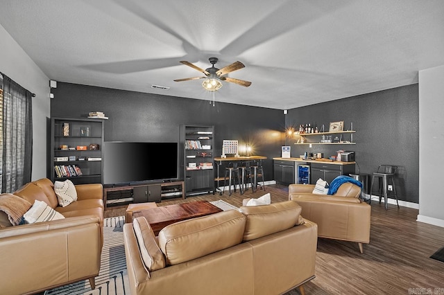 living room with wine cooler, wood finished floors, visible vents, baseboards, and a bar