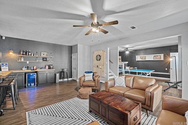 living area with dark wood finished floors, a dry bar, visible vents, stairway, and beverage cooler