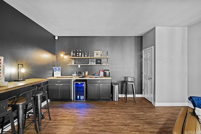 bar with wine cooler, dark wood-type flooring, a dry bar, and baseboards