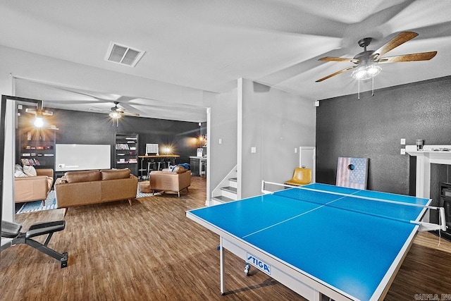 game room with a ceiling fan, visible vents, wood finished floors, and a tile fireplace