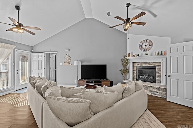 living area with visible vents, a ceiling fan, wood finished floors, a fireplace, and high vaulted ceiling