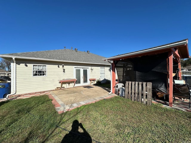 back of property featuring a patio, french doors, a lawn, and roof with shingles