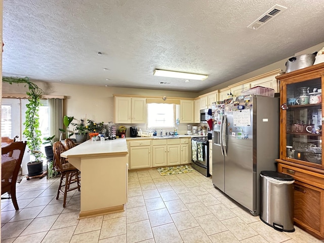 kitchen with light countertops, visible vents, cream cabinets, appliances with stainless steel finishes, and a peninsula