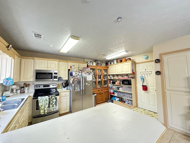 kitchen with stainless steel appliances, light countertops, visible vents, a sink, and a textured ceiling