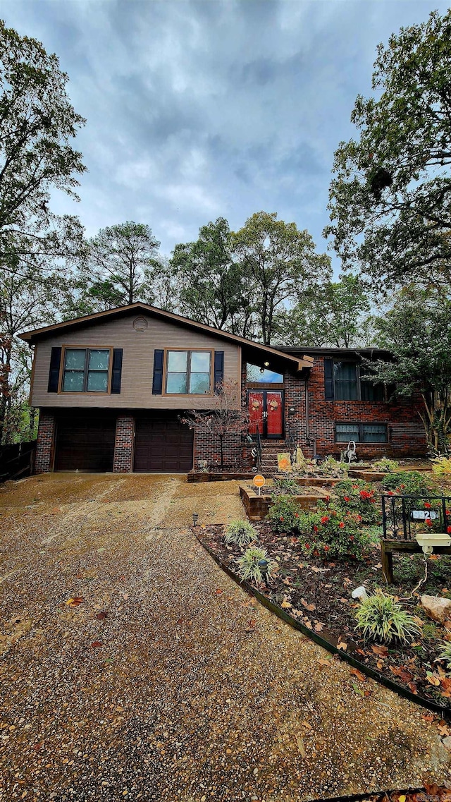 view of front facade with driveway, brick siding, and an attached garage