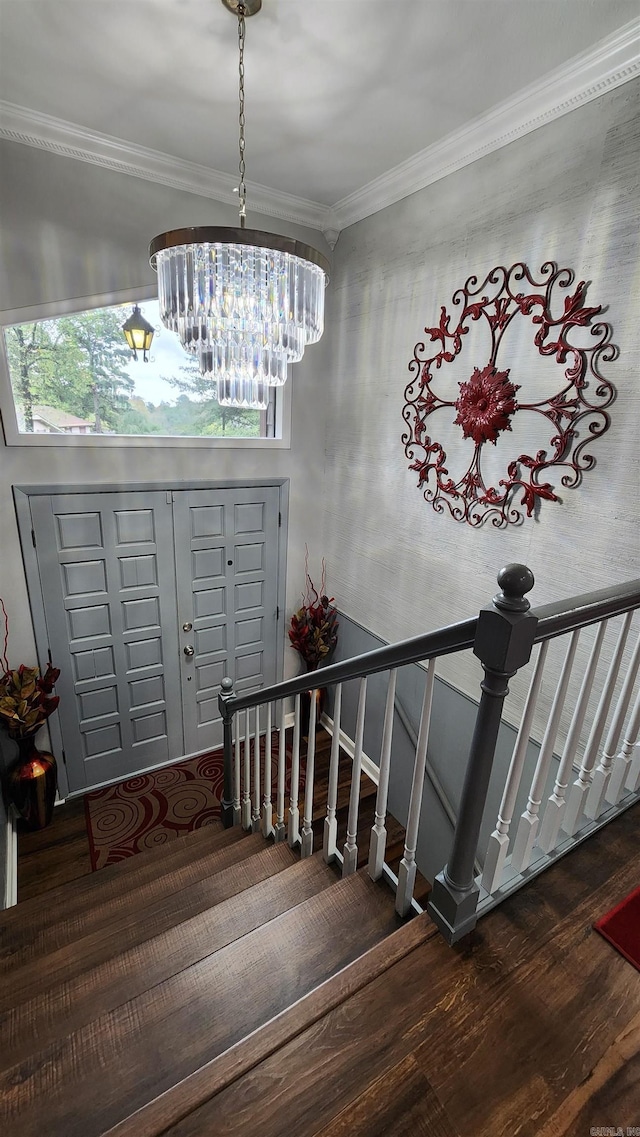 stairway featuring ornamental molding, wood finished floors, and an inviting chandelier