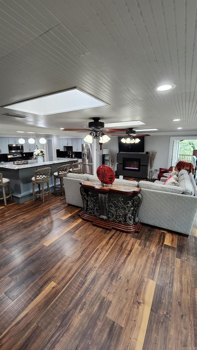 living room with dark wood-style flooring, wooden ceiling, a glass covered fireplace, and a ceiling fan