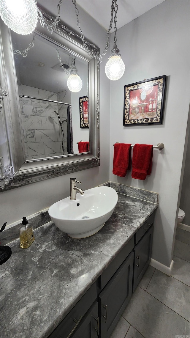 bathroom with baseboards, toilet, tile patterned floors, walk in shower, and vanity