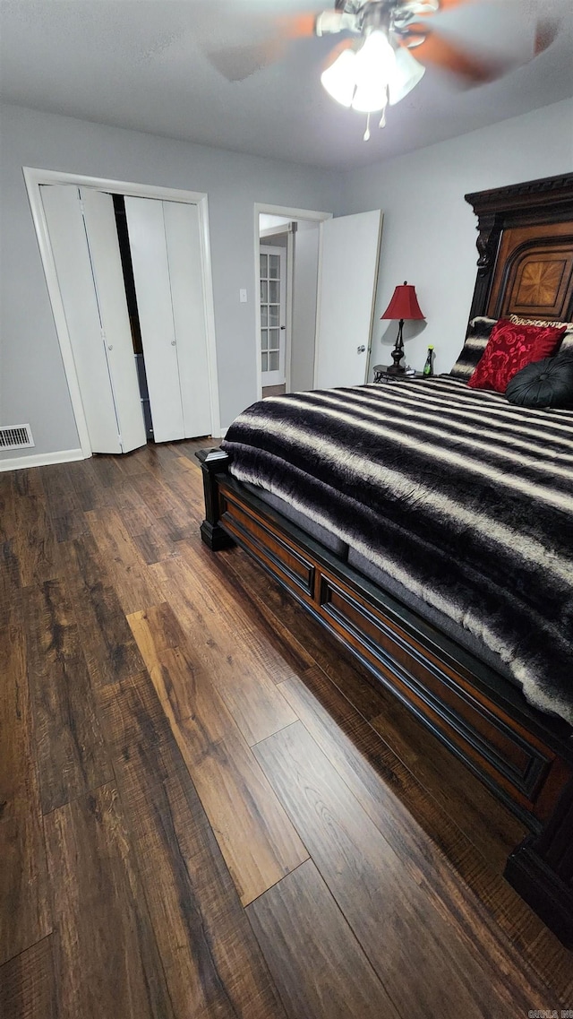 bedroom featuring a ceiling fan, visible vents, baseboards, and wood finished floors