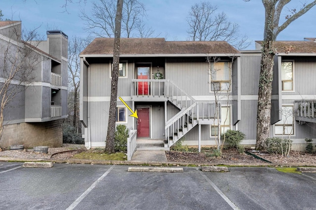 view of property with uncovered parking and stairway