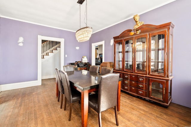 dining room featuring a notable chandelier, crown molding, baseboards, and wood finished floors