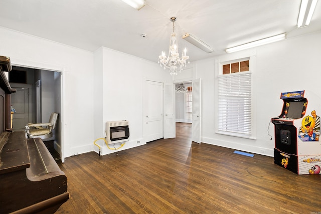 miscellaneous room featuring an inviting chandelier, baseboards, heating unit, and wood finished floors