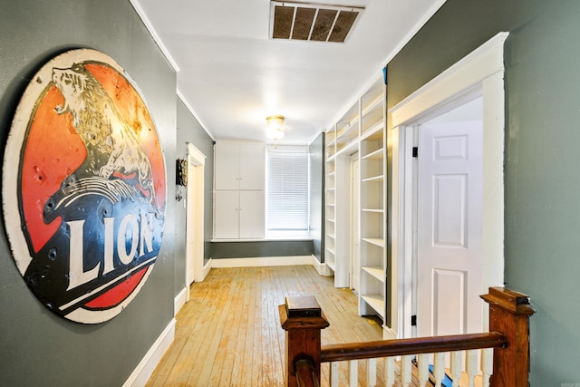 corridor featuring light wood-style floors, baseboards, and visible vents