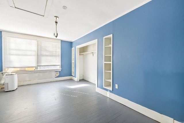 spare room featuring ornamental molding, built in shelves, wood finished floors, and baseboards