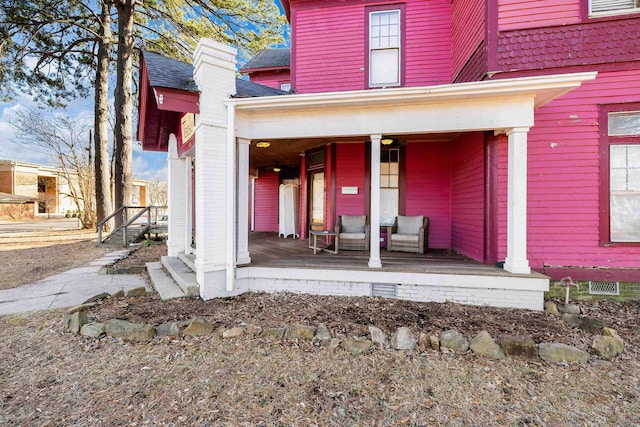 entrance to property featuring a porch and roof with shingles