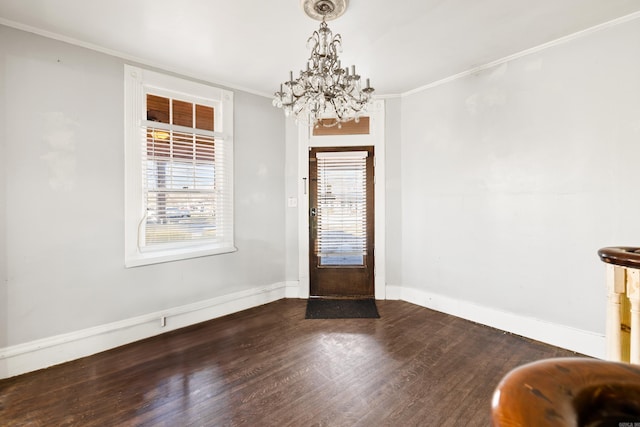 foyer featuring a notable chandelier, baseboards, crown molding, and wood finished floors