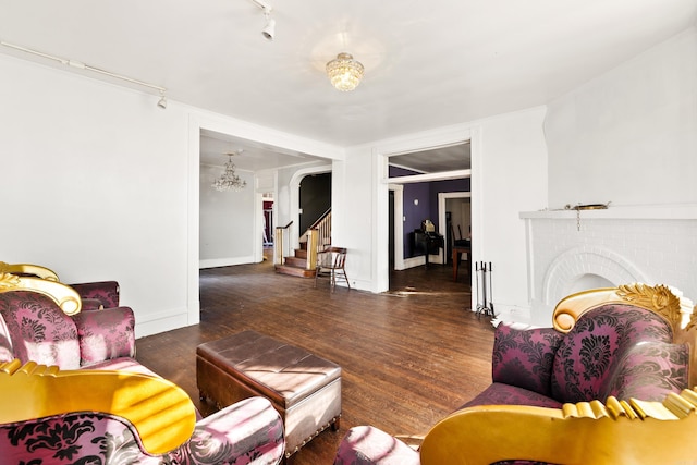 living room with arched walkways, baseboards, wood finished floors, stairs, and a fireplace