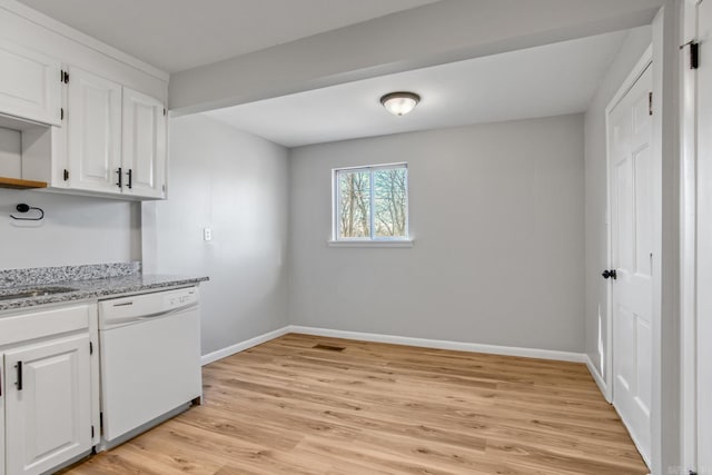 kitchen with light stone counters, light wood finished floors, white cabinets, white dishwasher, and baseboards