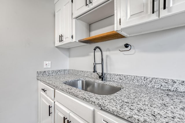 interior space featuring open shelves, light stone counters, a sink, and white cabinets