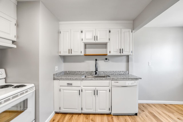 kitchen with light stone counters, white appliances, a sink, and light wood finished floors