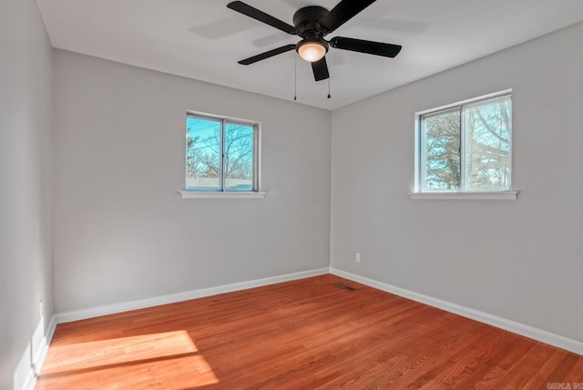 unfurnished room with plenty of natural light, baseboards, and wood finished floors