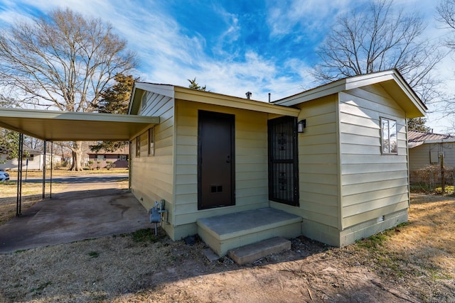 view of front facade featuring an attached carport, crawl space, and dirt driveway