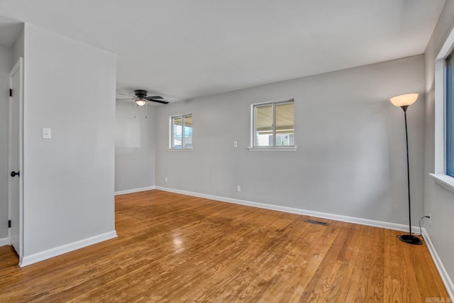 empty room featuring light wood-style floors, visible vents, ceiling fan, and baseboards