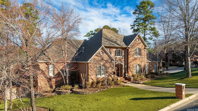 view of front facade featuring roof with shingles, a front lawn, and brick siding