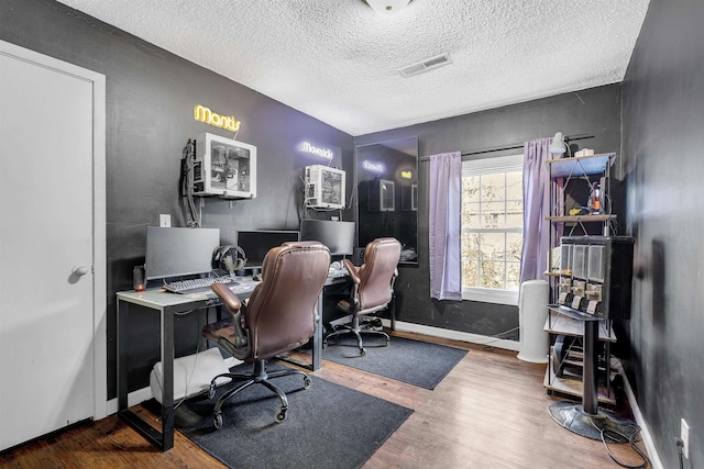 office area featuring a textured ceiling, wood finished floors, visible vents, and baseboards