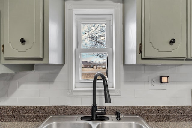 kitchen featuring dark countertops, tasteful backsplash, and a sink