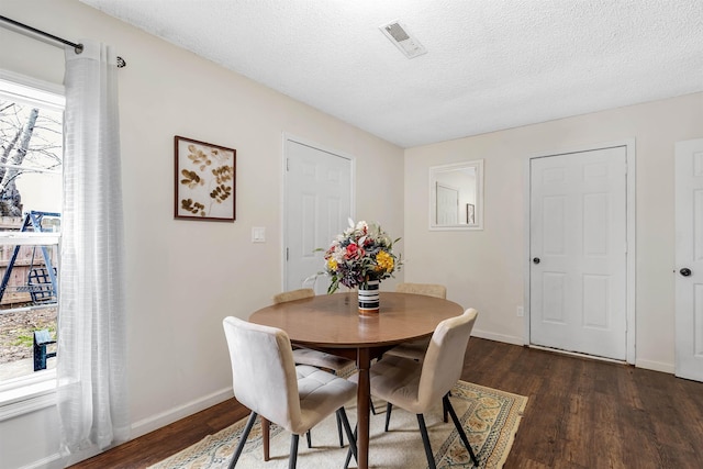 dining room featuring a textured ceiling, dark wood finished floors, visible vents, and baseboards