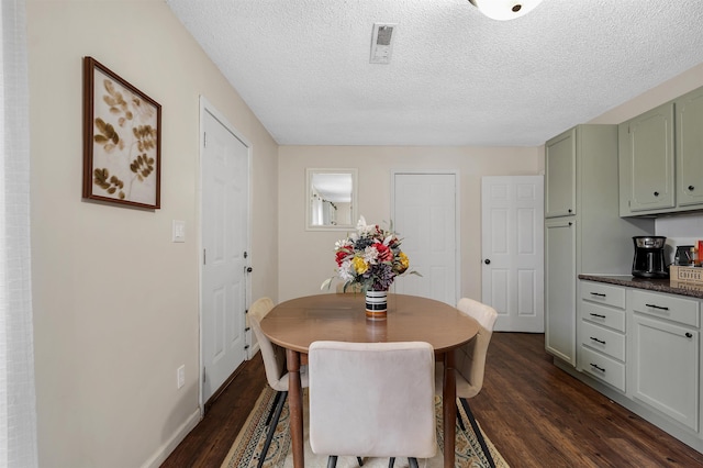 dining space with visible vents, dark wood finished floors, a textured ceiling, and baseboards