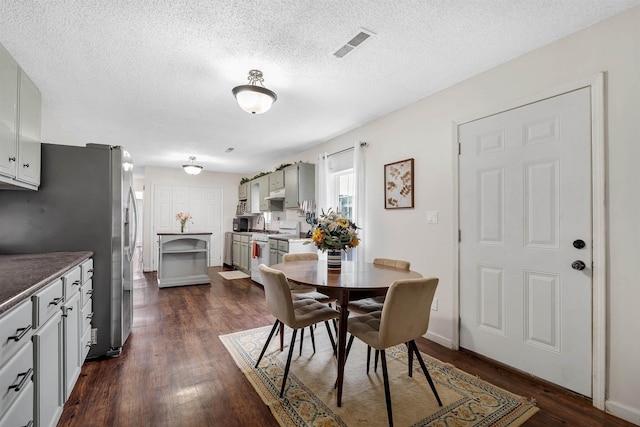 dining space featuring dark wood-type flooring, visible vents, and a textured ceiling