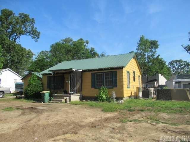 bungalow-style home featuring metal roof and fence