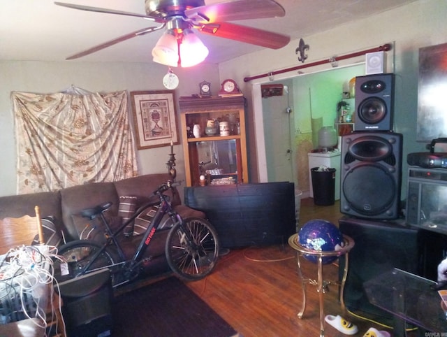 living area featuring ceiling fan, stacked washer and dryer, and wood finished floors