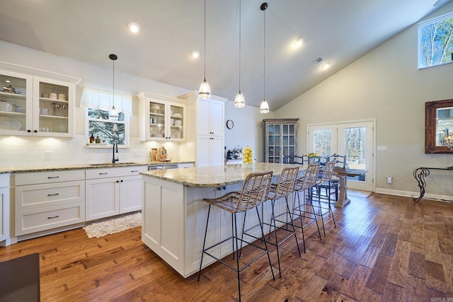 kitchen featuring dark wood-style flooring, a sink, white cabinets, and a center island