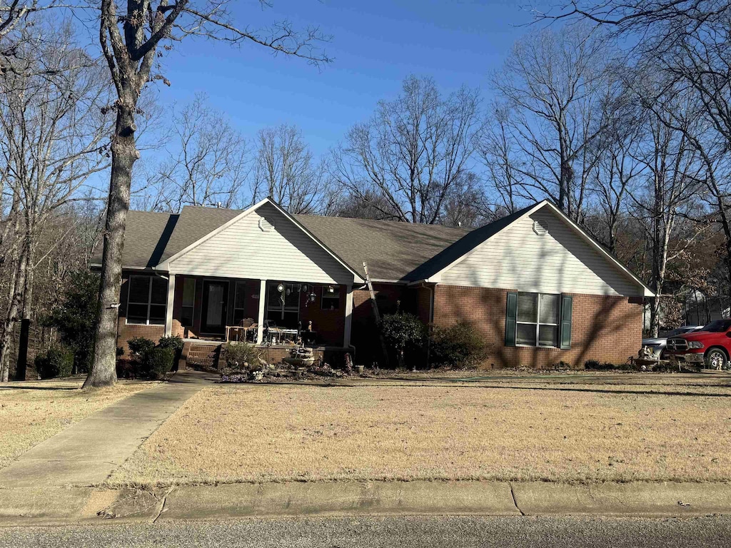 ranch-style house with a front lawn, a porch, and brick siding