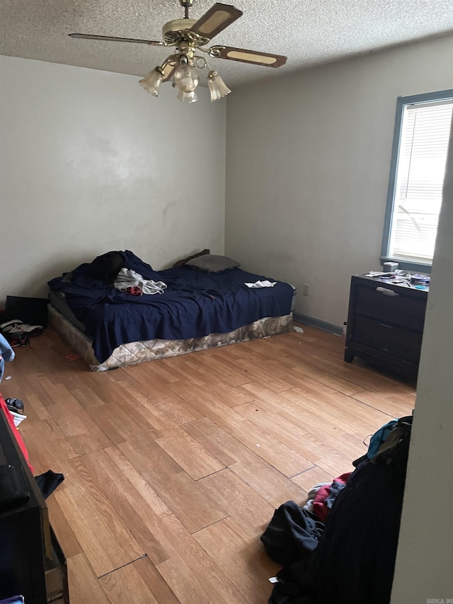 bedroom with a ceiling fan, light wood-style flooring, and a textured ceiling