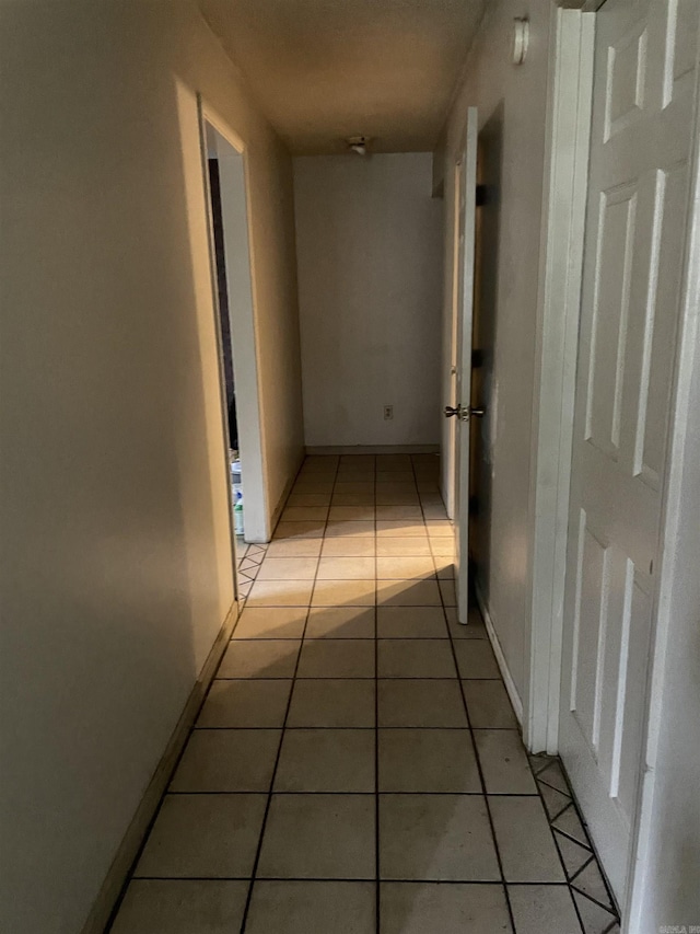 hall with light tile patterned flooring and baseboards