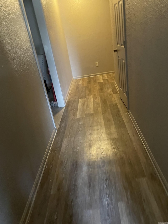 corridor featuring wood finished floors and baseboards