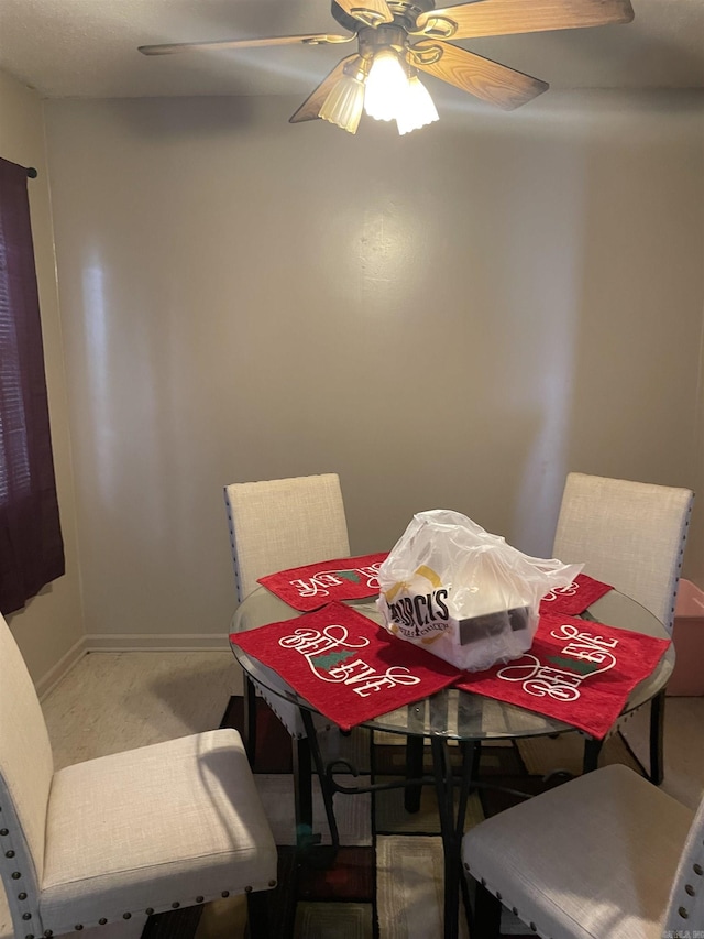 dining room with a ceiling fan, light carpet, and baseboards