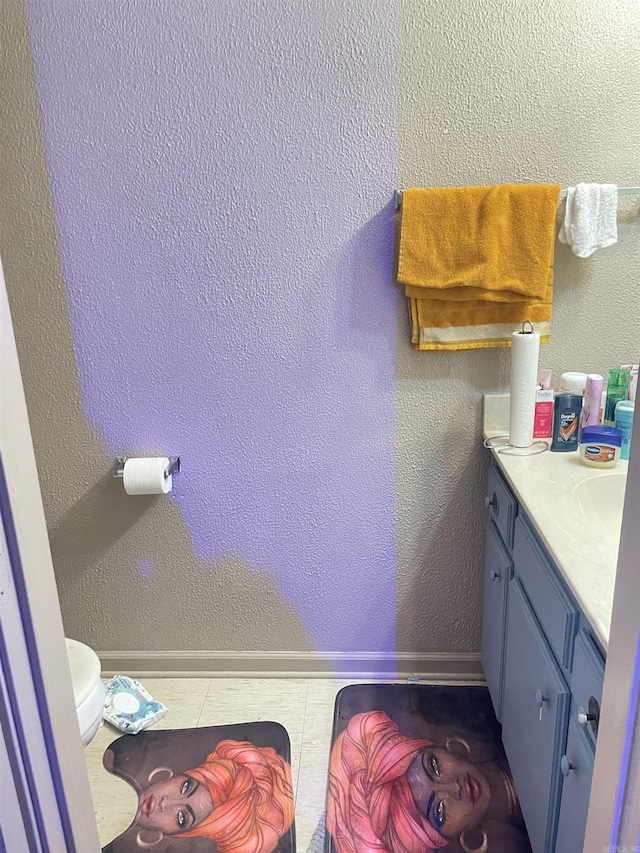 bathroom with baseboards, a textured wall, vanity, and tile patterned floors