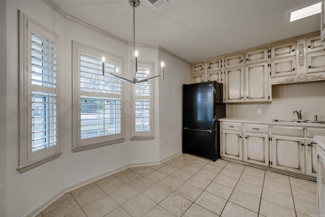 kitchen featuring crown molding, light tile patterned floors, cream cabinets, freestanding refrigerator, and a sink