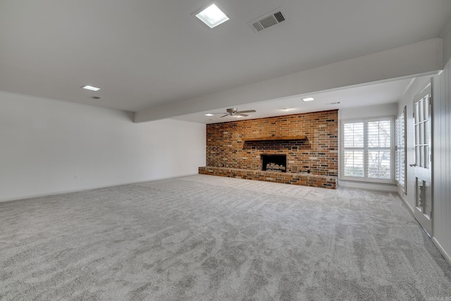 unfurnished living room with carpet floors, a brick fireplace, visible vents, and a ceiling fan